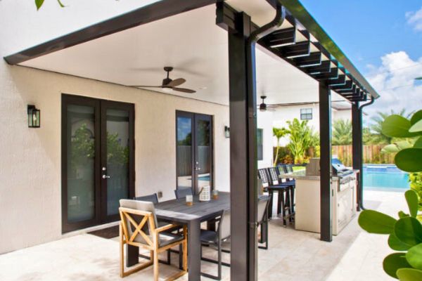 Contempo Renaissance Pergola Black and white pergola with patio table and chairs underneath